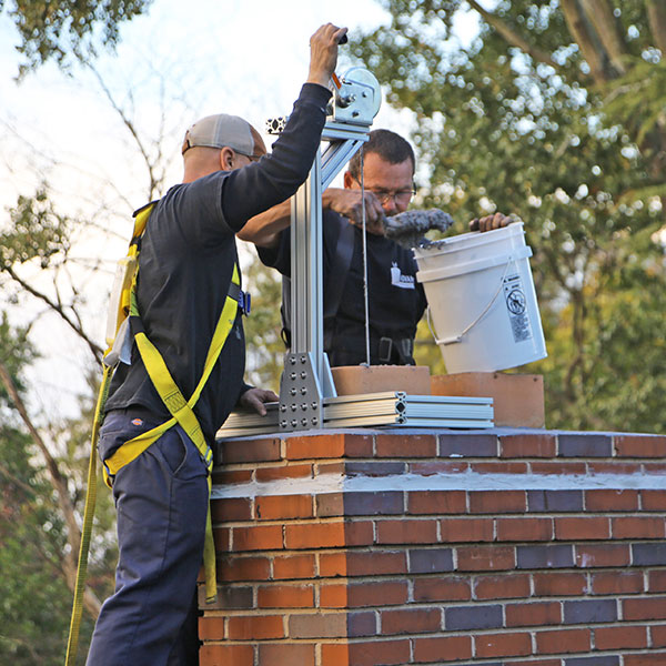 Two chimney technicians work on relining a chimney with the CeCure® Sleeve Relining System.
