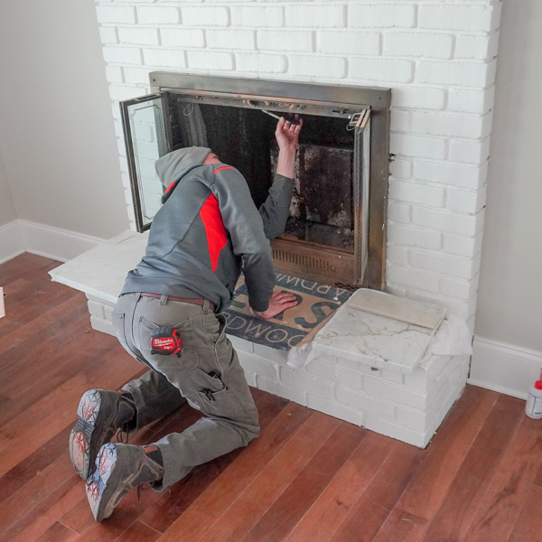 Chimney professional applies Smoktite sealant during a fireplace repair.